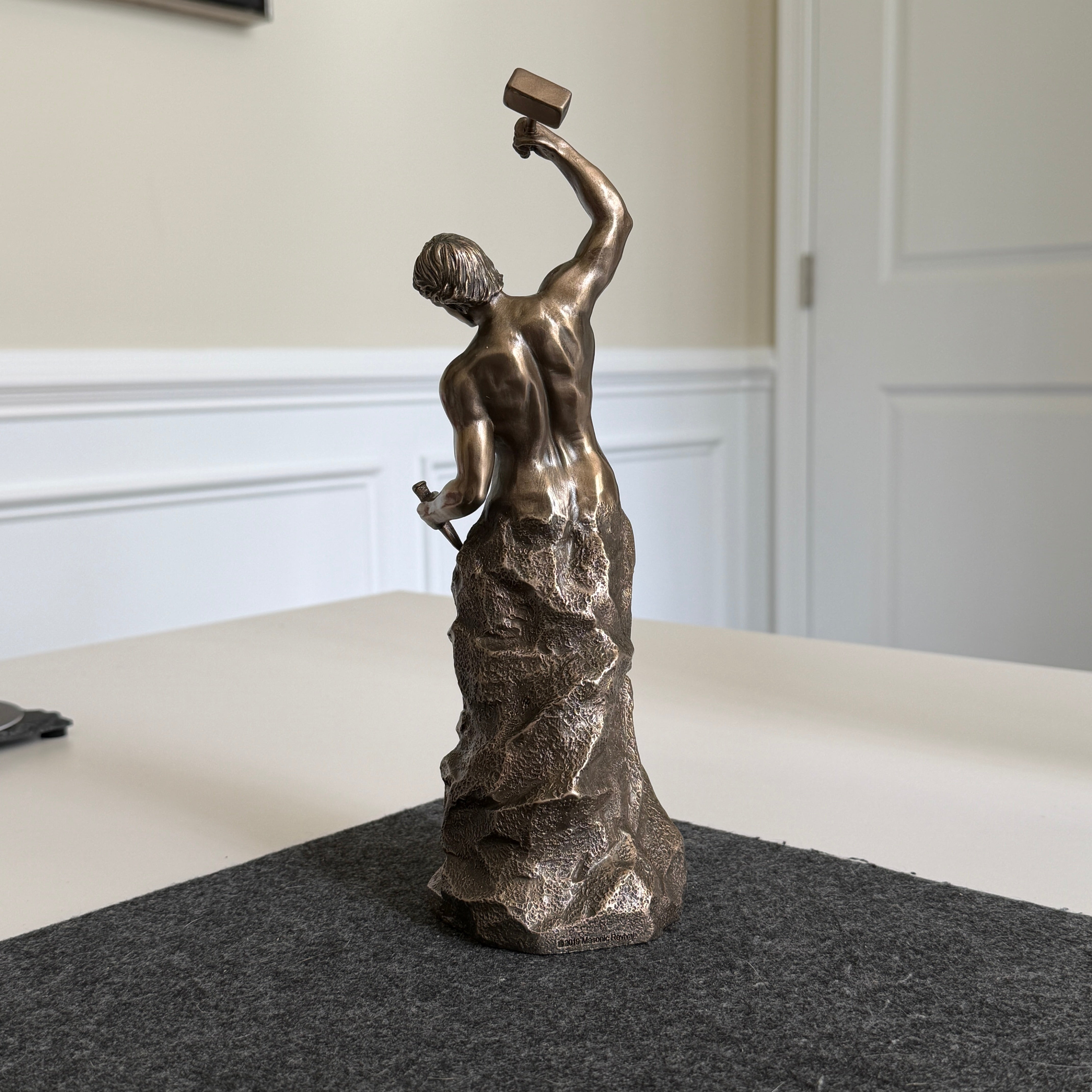 Bronze statue of a woman holding a hammer on a table with a neutral background Self made man statue, gift for entrepreneurs and business professionals. Man chiseling himself. Man building himself. Figurine stature. 